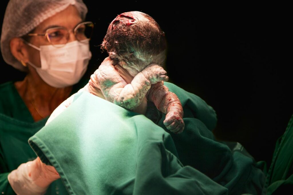 Ostetrica con un neonato appena dato alla luce (Foto Pexels di Hannah Barata)
