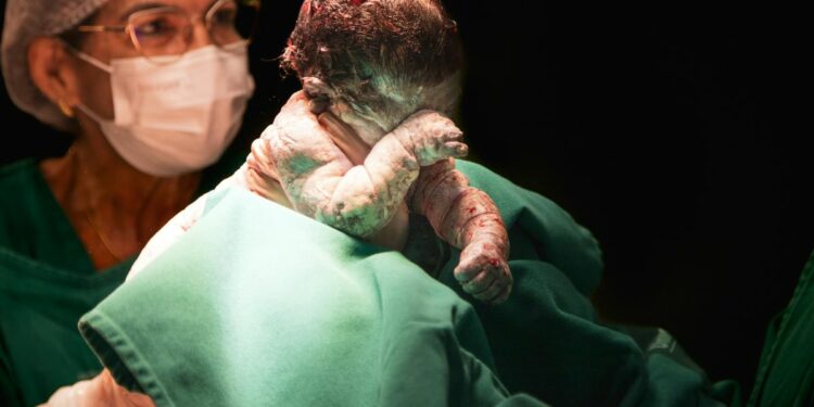 Ostetrica con un neonato appena dato alla luce (Foto Pexels di Hannah Barata)