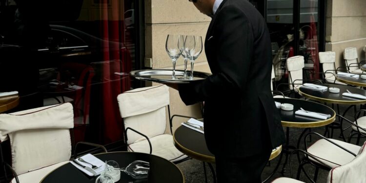 Un cameriere tra i tavoli all'aperto di un ristornate (Foto Pexels di Yelenaodintsova )